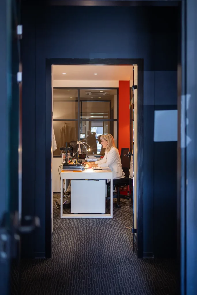 Femme travaillant à son bureau le soir, mur bleu et porte rouge