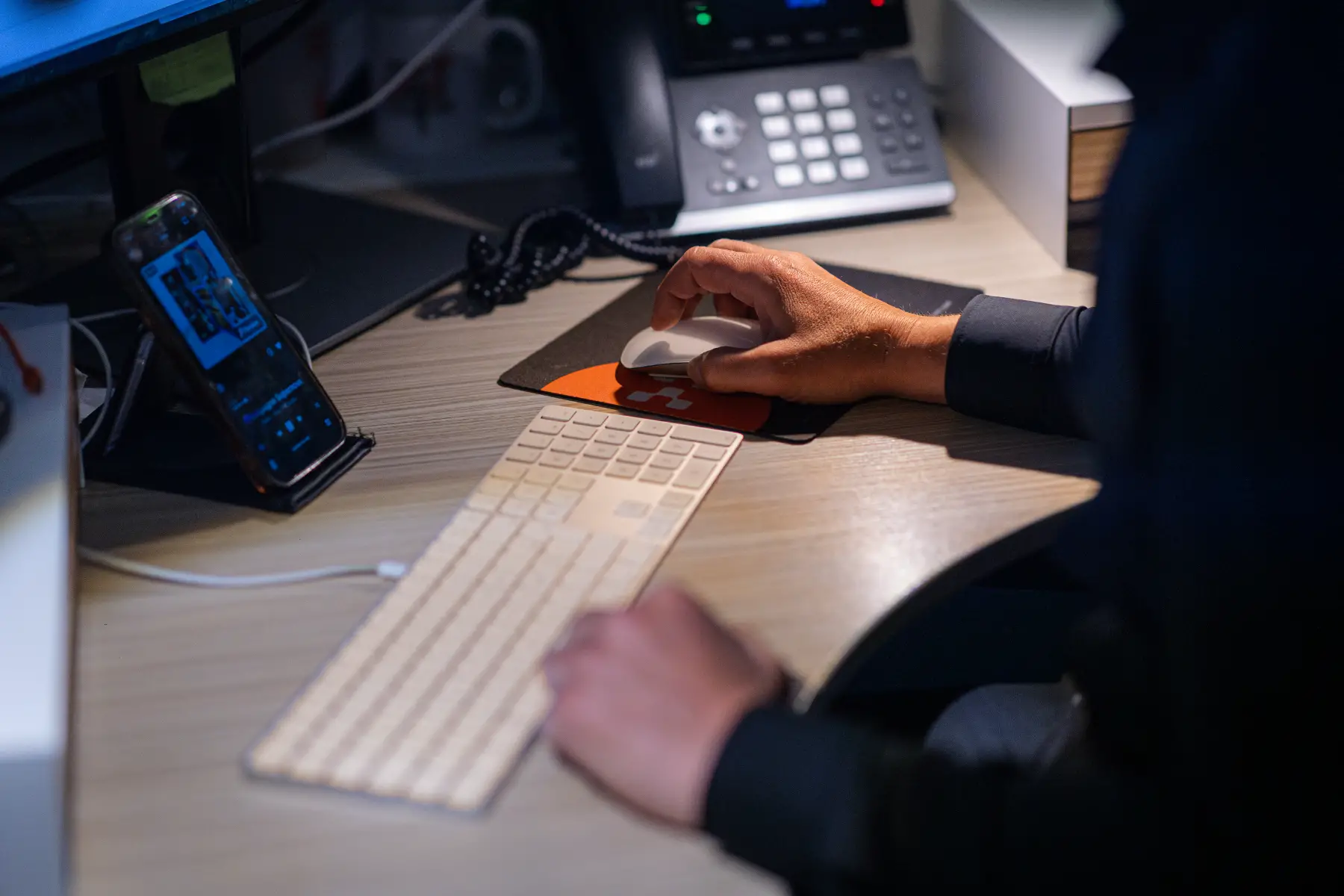 Gros plan d'une main sur une souris, téléphone de bureau à proximité