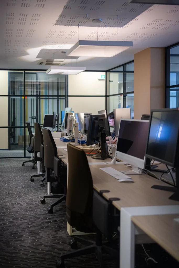 Open space avec plusieurs postes informatiques et cloisons vitrées