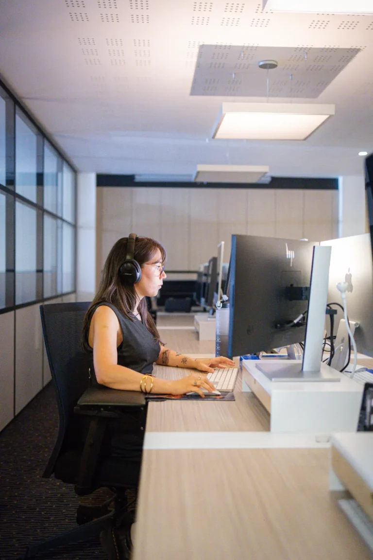 Femme concentrée avec casque, travaillant sur un ordinateur de bureau