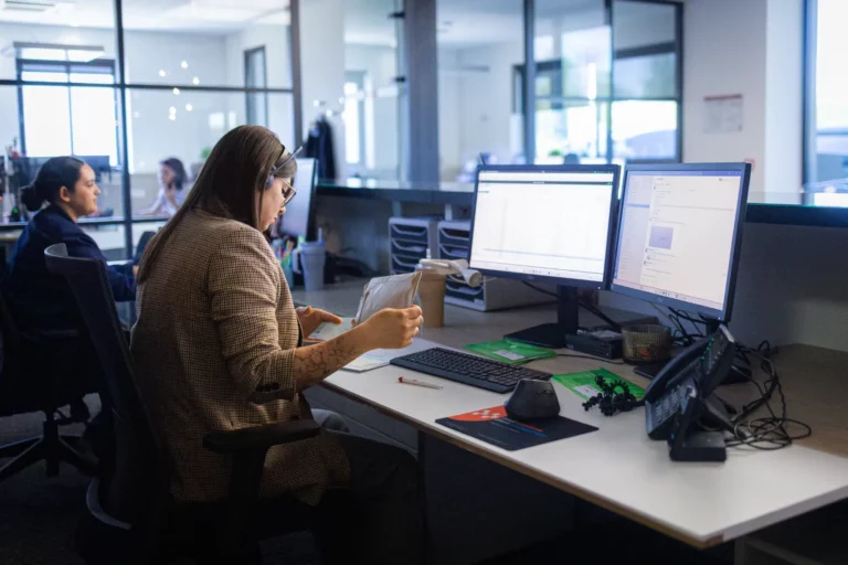 Femme travaillant sur deux écrans d'ordinateur à son bureau